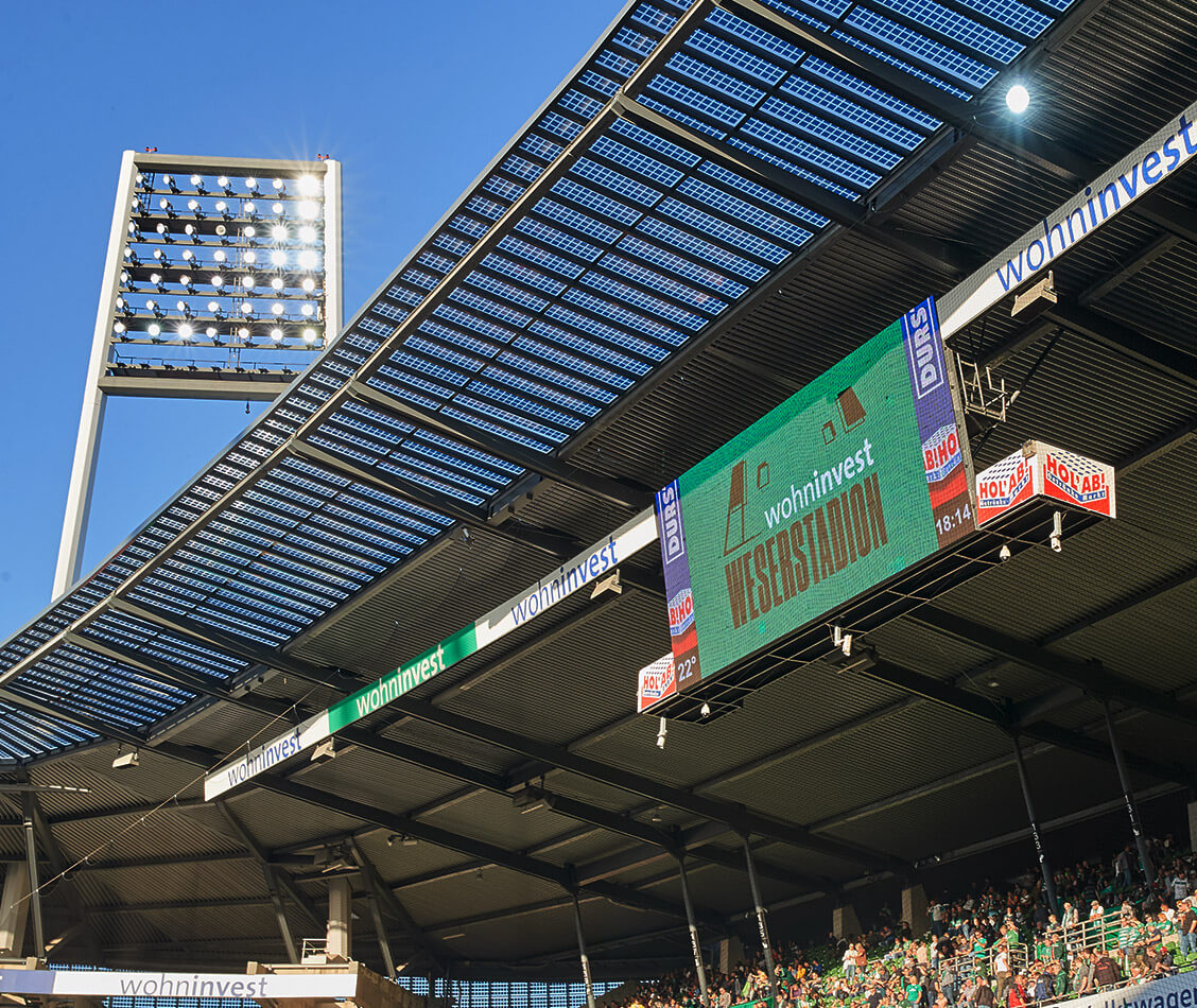 Dieses Bild zeigt die LED-Wall mit dem wohninvest WESERSTADION-Logo und den Dachkranz mit dem Wohninvest-Logo.